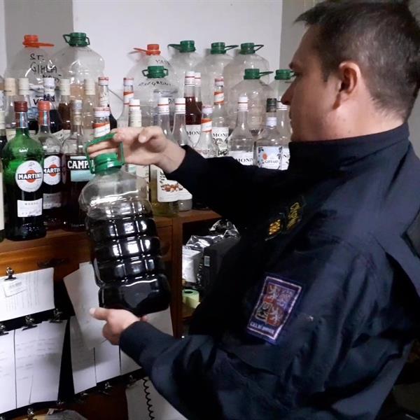 Celník drží lahev s alkoholem