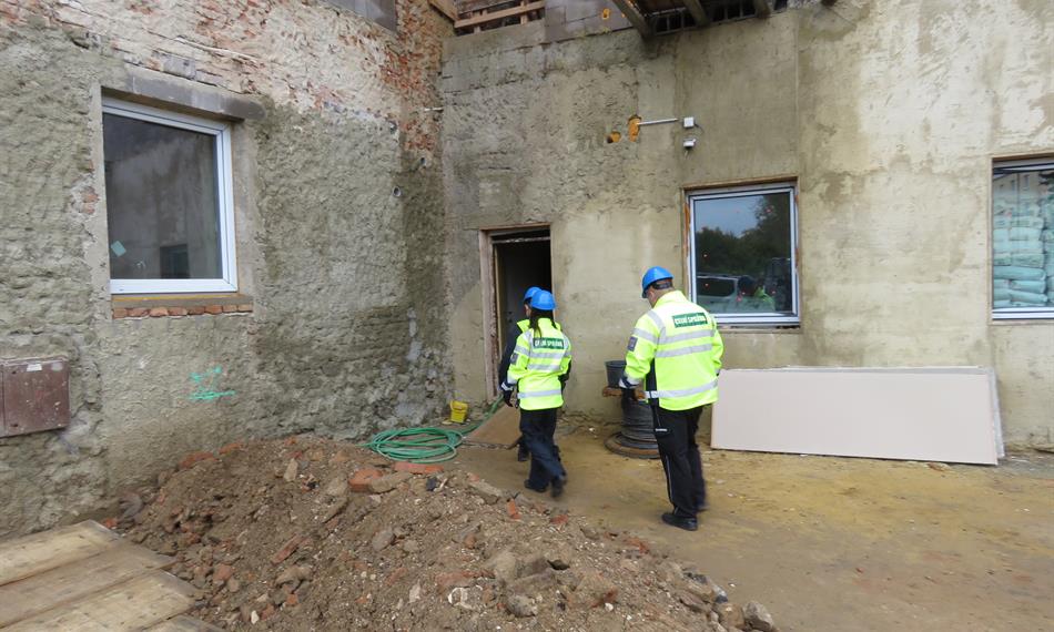 tři celníci vstupují do objektu